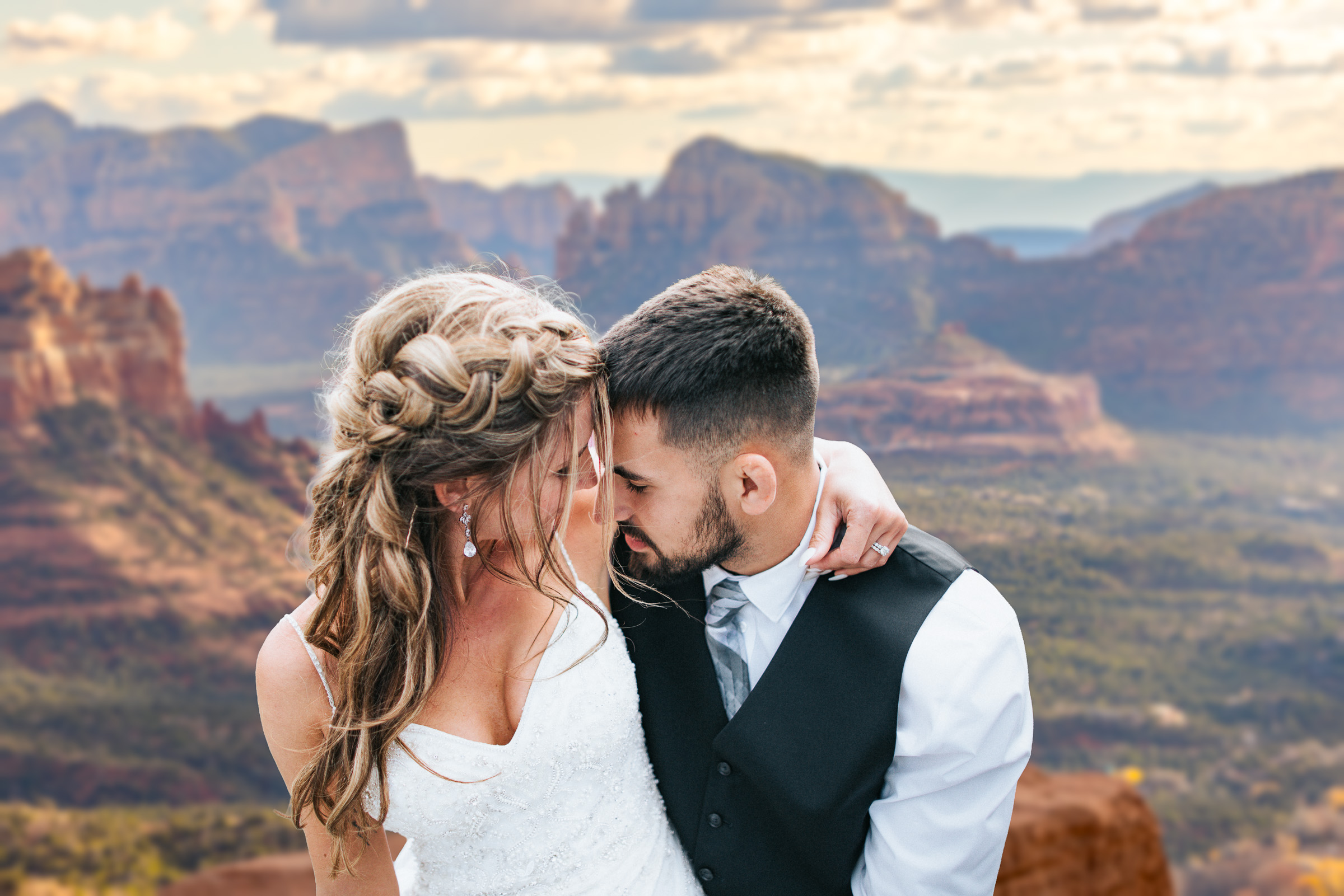 Couple embracing forehead-to-forehead against Sedona's red rock canyons at sunset